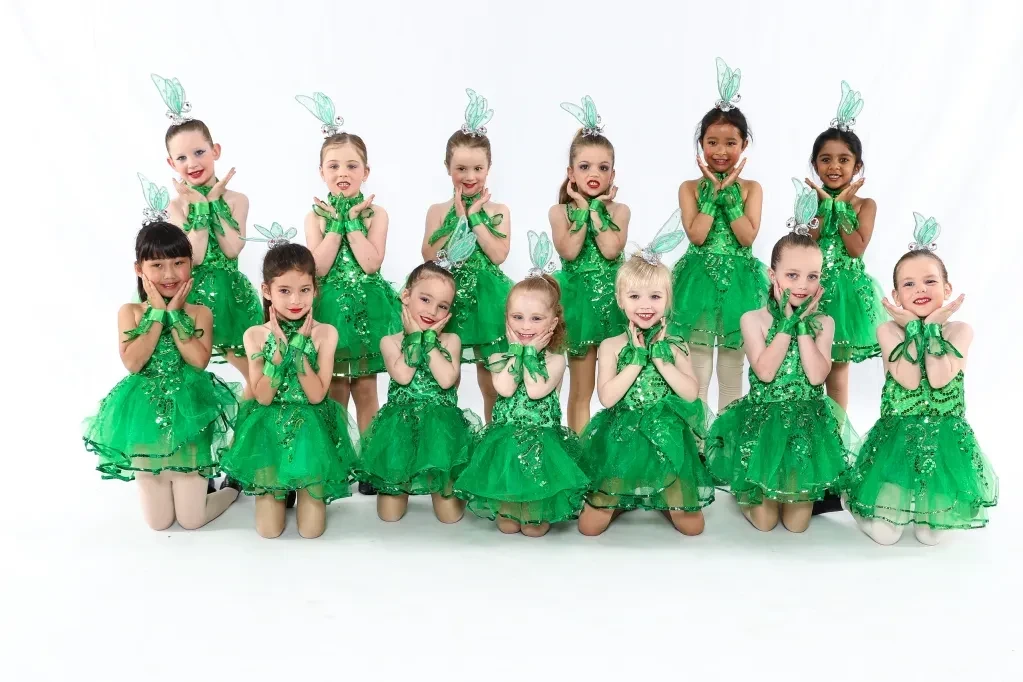 Children in green sequined fairy costumes posing on white background