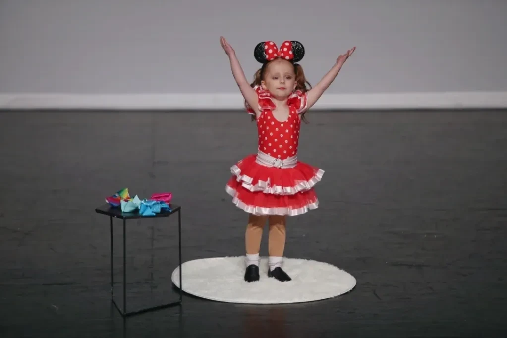 Tiny toddler in Minnie Mouse costume performing on stage